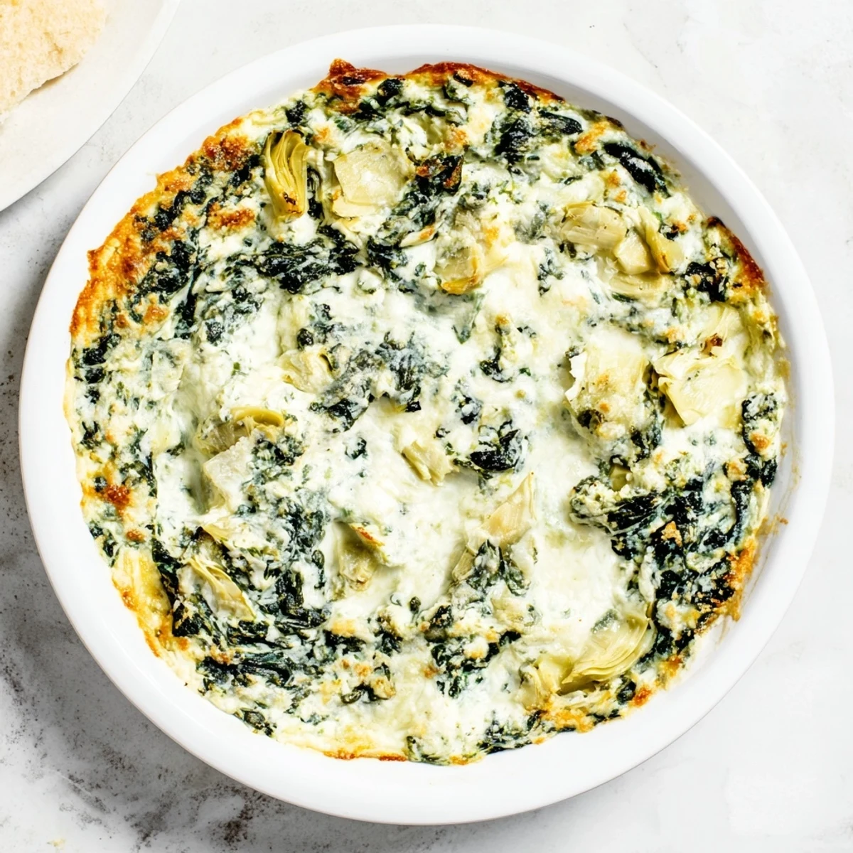 A close-up of cheesy, creamy Warm Spinach and Artichoke Dip, perfect for dipping tortilla chips.