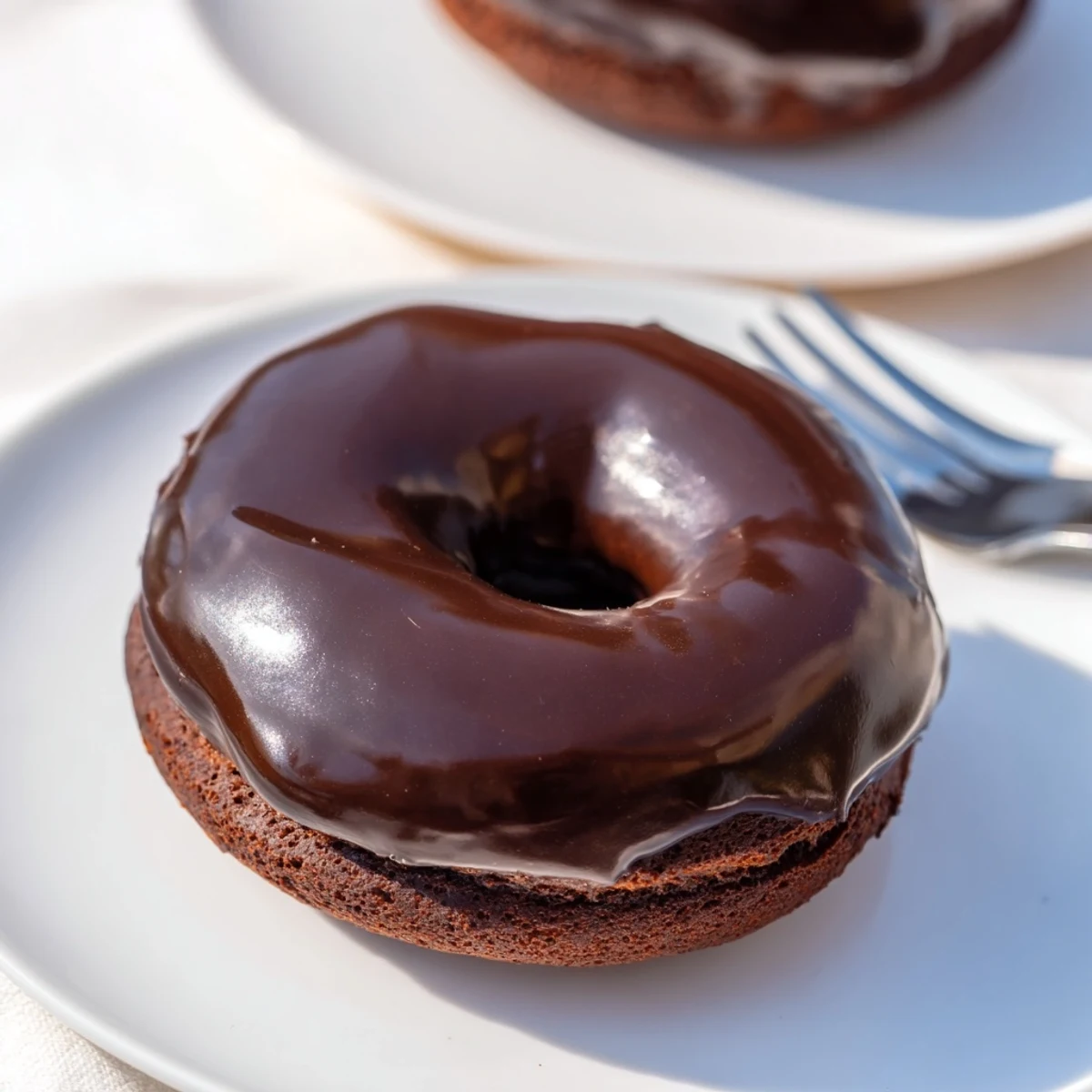 A glossy chocolate donut, freshly glazed and perfect for enjoying a classic American dessert.