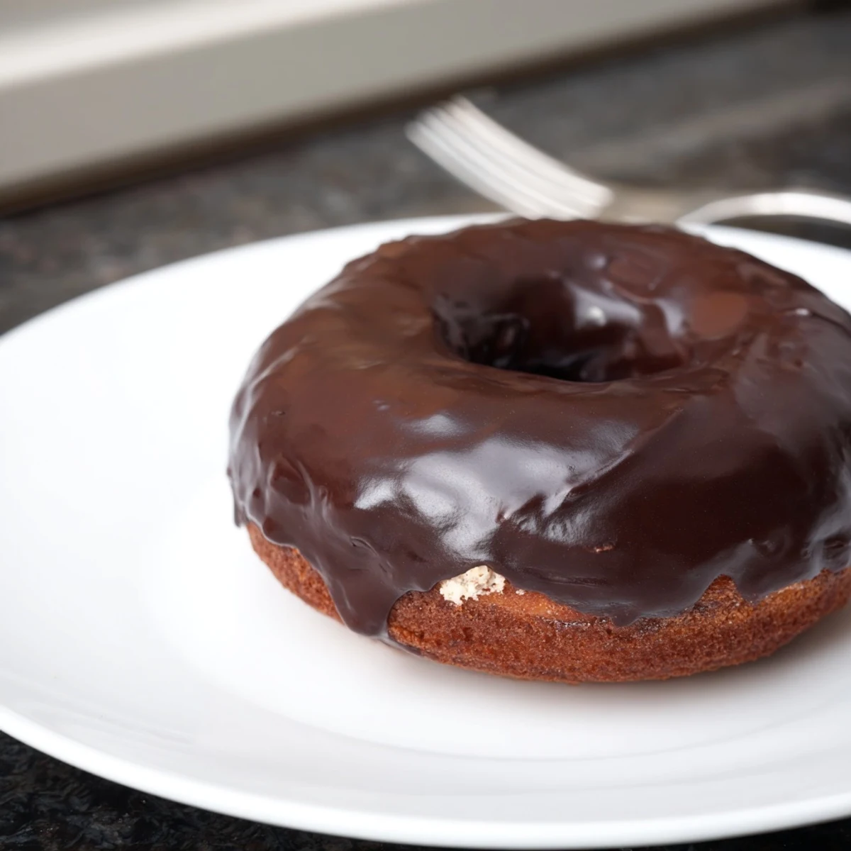 Close-up of a chocolate donut’s rich, dark chocolate glaze, a tempting homemade breakfast snack.