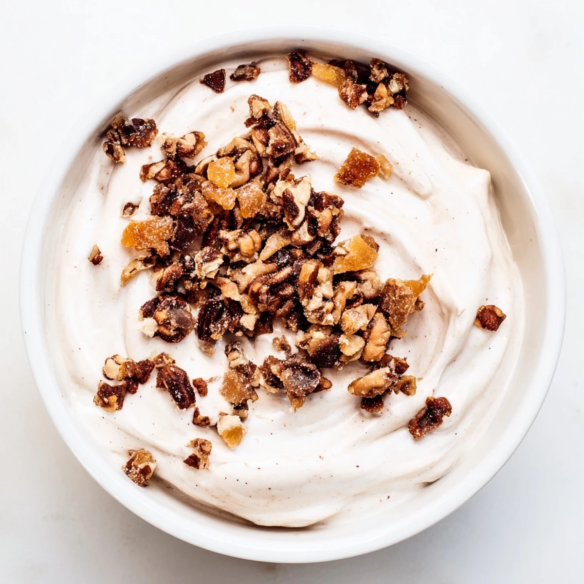 A bowl of gingerbread flavored yogurt topped with toasted pecans, offering a delicious treat.