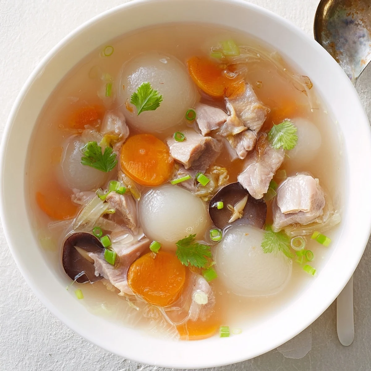 This warm bowl of Winter Melon Soup features a delicate broth and fresh garnishes for serving.