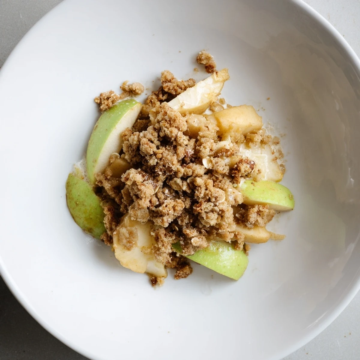 Close-up of a rustic Warm Apple Crumble, showing the juicy apple filling beneath a buttery, oat crumble.