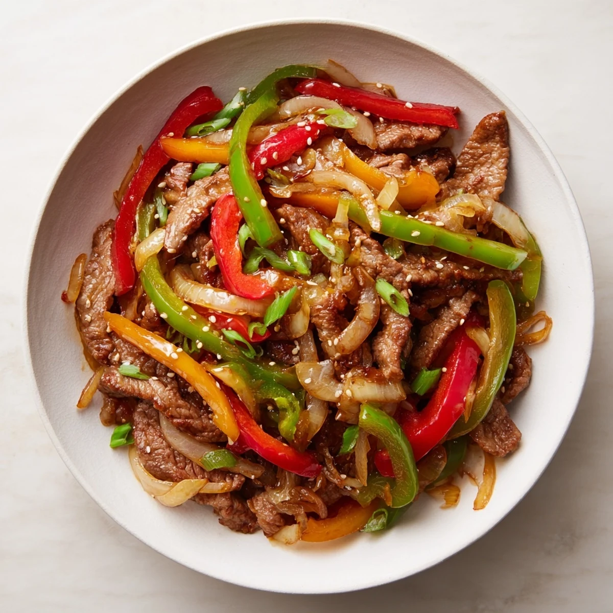Close up shot of the Spicy Beef and Pepper Stir Fry with visible spring onions and sesame seeds sprinkled on top.
