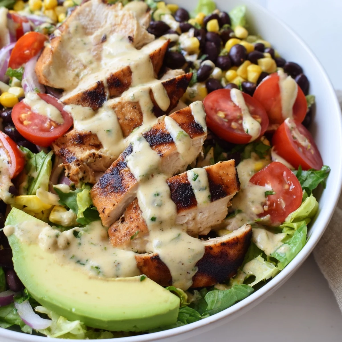 A plated Southwest Chicken Salad with Chipotle Lime Dressing features grilled chicken slices over crisp romaine and bright cherry tomatoes.