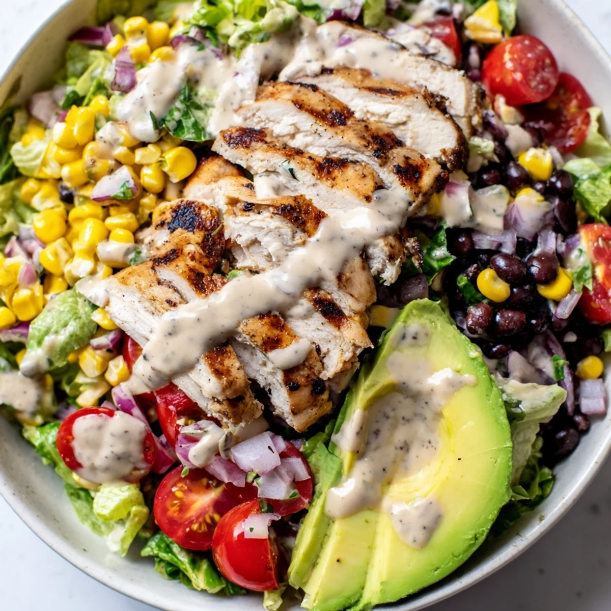 Vibrant bowl of Southwest Chicken Salad with Chipotle Lime Dressing, garnished with avocado, black beans, and fresh cilantro leaves.