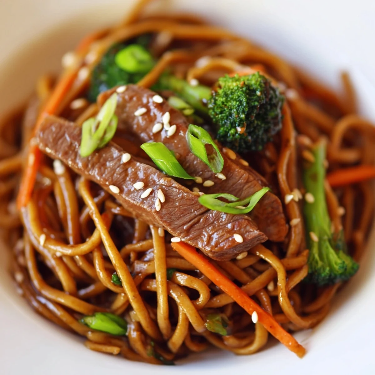 Freshly cooked Beef and Broccoli Lo Mein with Sesame Oil served hot with chopsticks on a plate.
