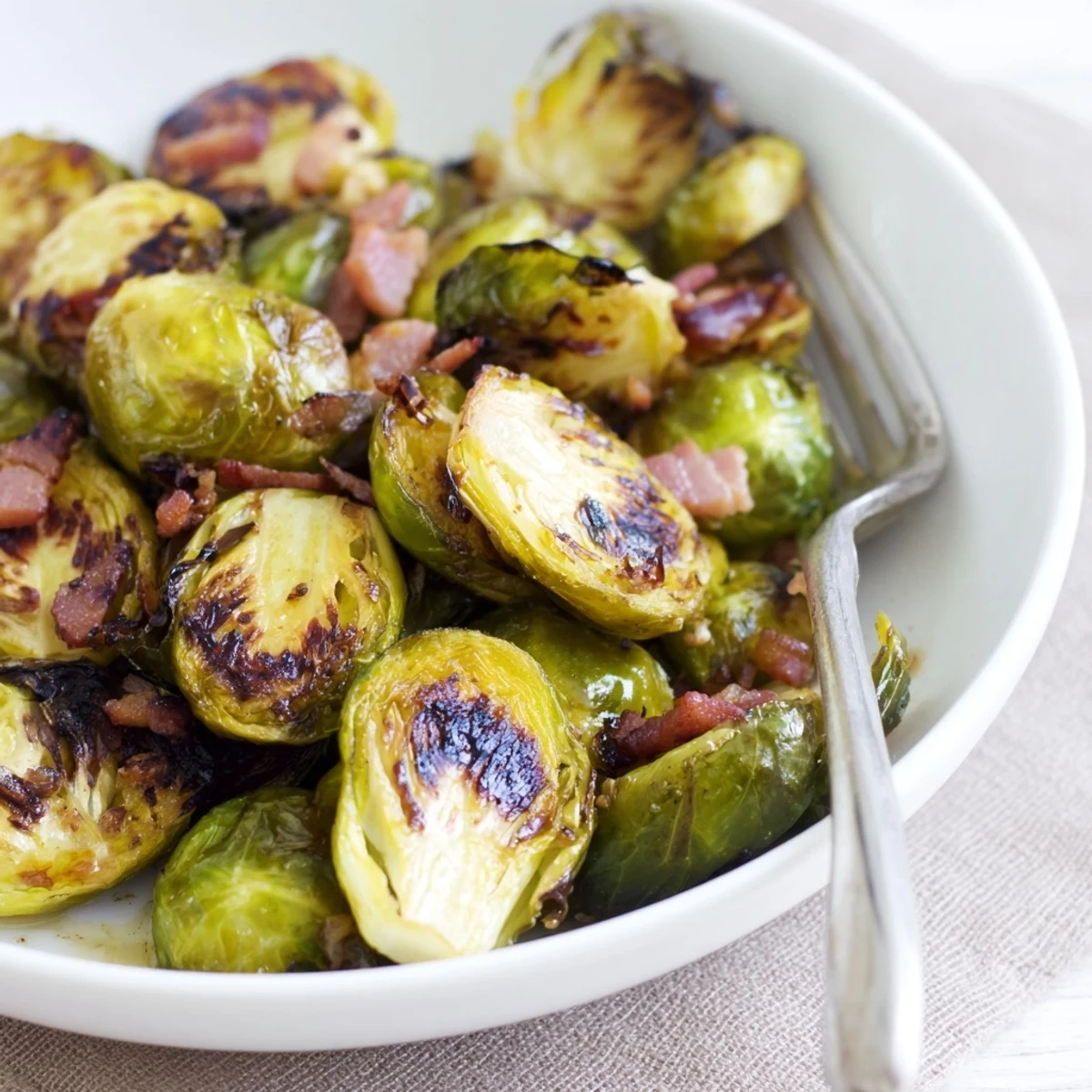 Golden-brown roasted Brussels sprouts with crispy turkey bacon, garnished with fresh lemon juice and served on a rustic wooden platter.