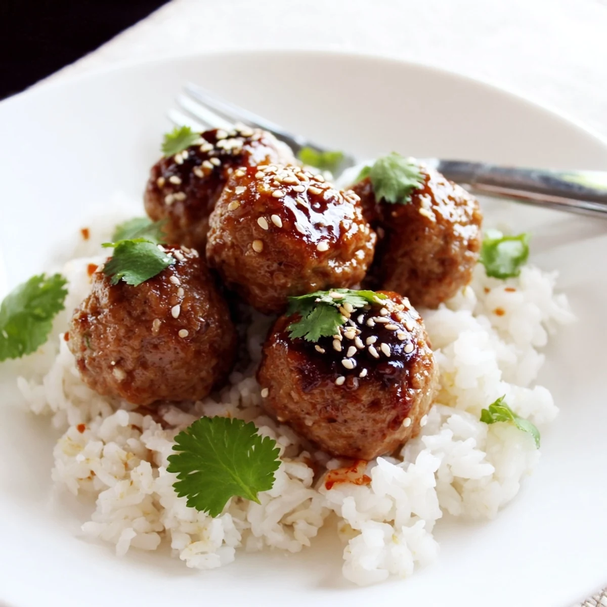 Juicy Spicy Sriracha Beef Meatballs baked with a honey-soy glaze, paired with steamed rice for a quick dinner.