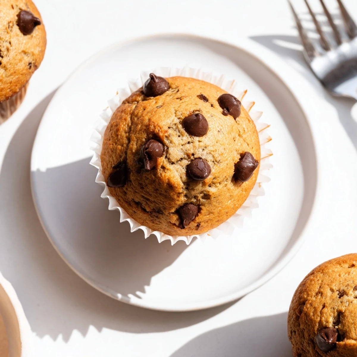 Freshly baked Chocolate Chip Banana Bread Muffins with melted chocolate chips on a wooden cooling rack.