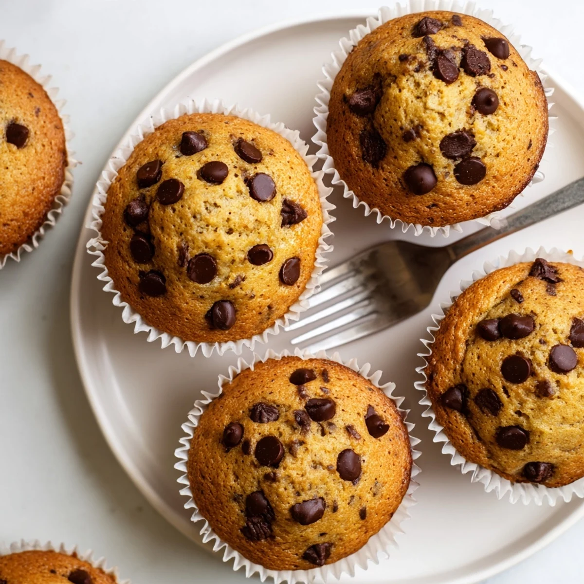 Moist Chocolate Chip Banana Bread Muffins on a rustic plate, showcasing ripe banana texture.