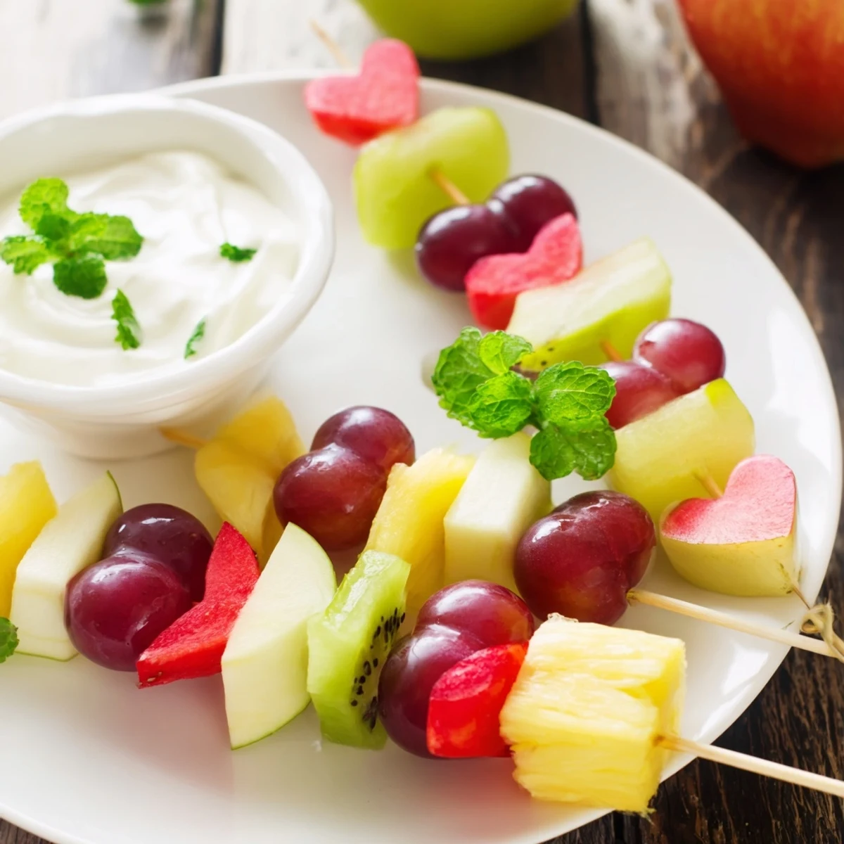 Vibrant Sweetheart Fruit Skewers with Yogurt Dip garnished with fresh mint, perfect for a healthy party snack or sweet dessert.