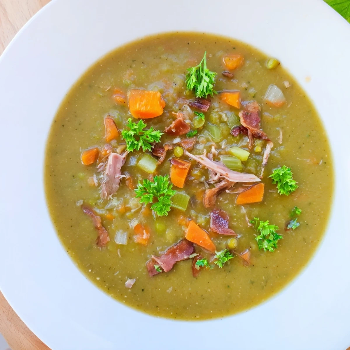 Steaming bowls of green split pea soup with smoked turkey leg garnished with fresh parsley.  