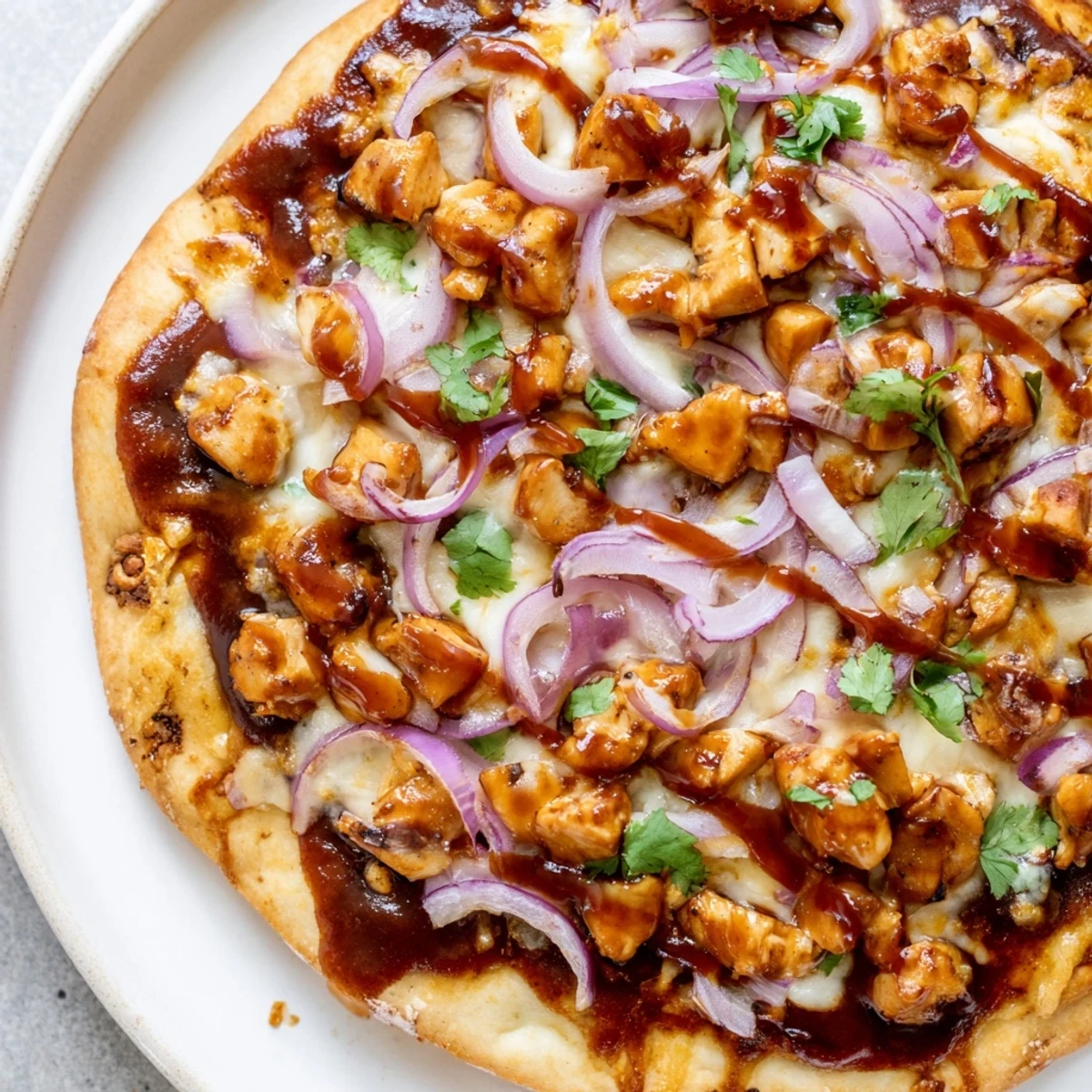 Golden BBQ Chicken Pizza topped with red onion, cilantro, and melted mozzarella on a crispy crust.