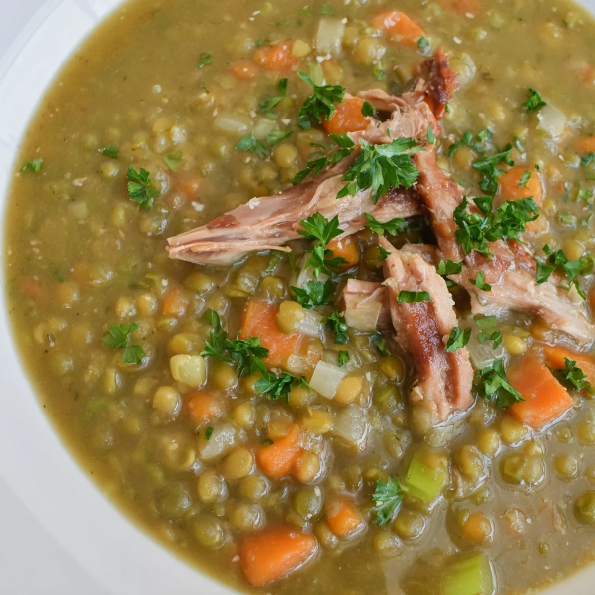 A steaming pot of Green Split Pea Soup with Smoked Turkey Leg, featuring tender carrots and celery in a thick broth.