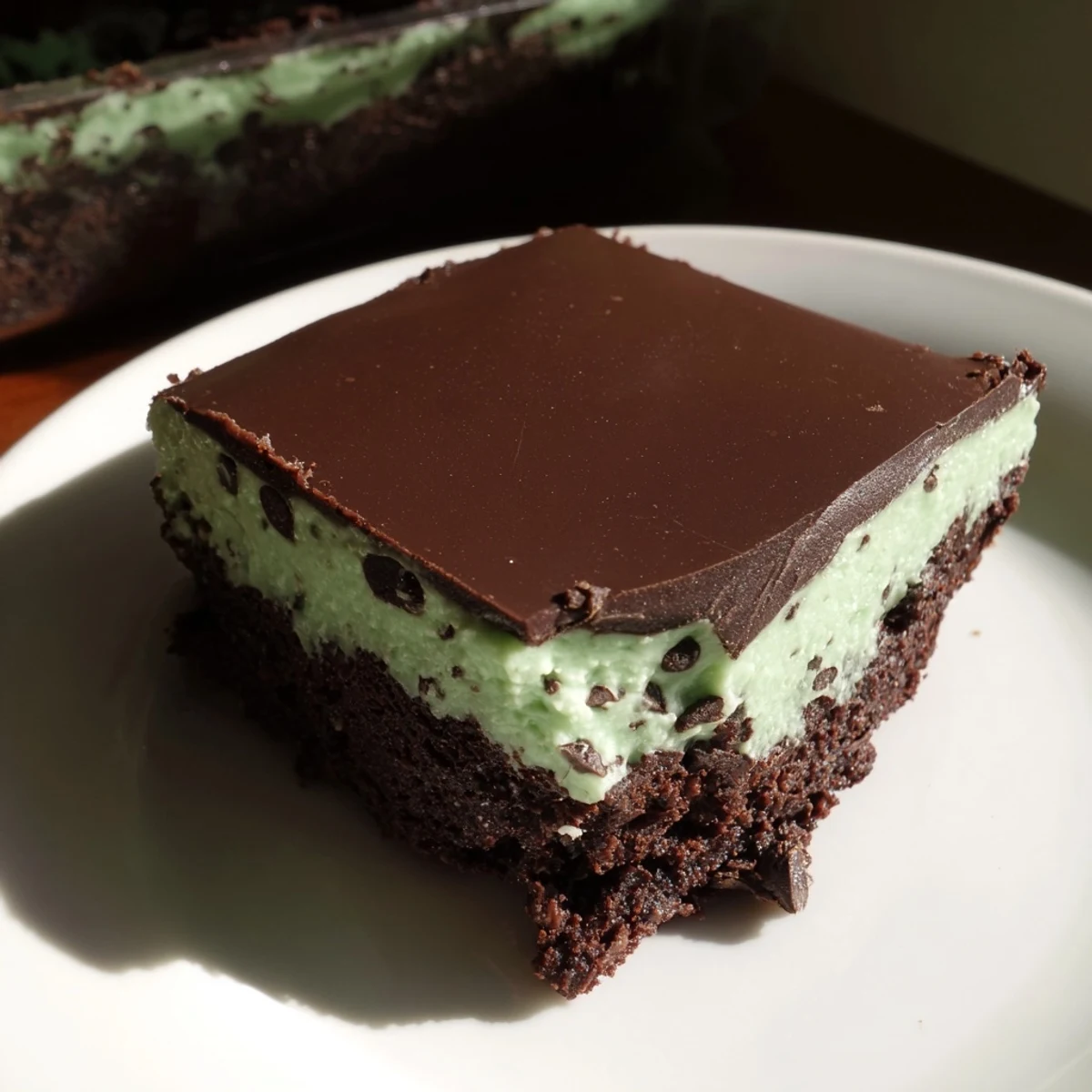 Mint Chocolate Chip Brownies on a white plate, with a glass of milk, offer a refreshing and decadent dessert for a party.