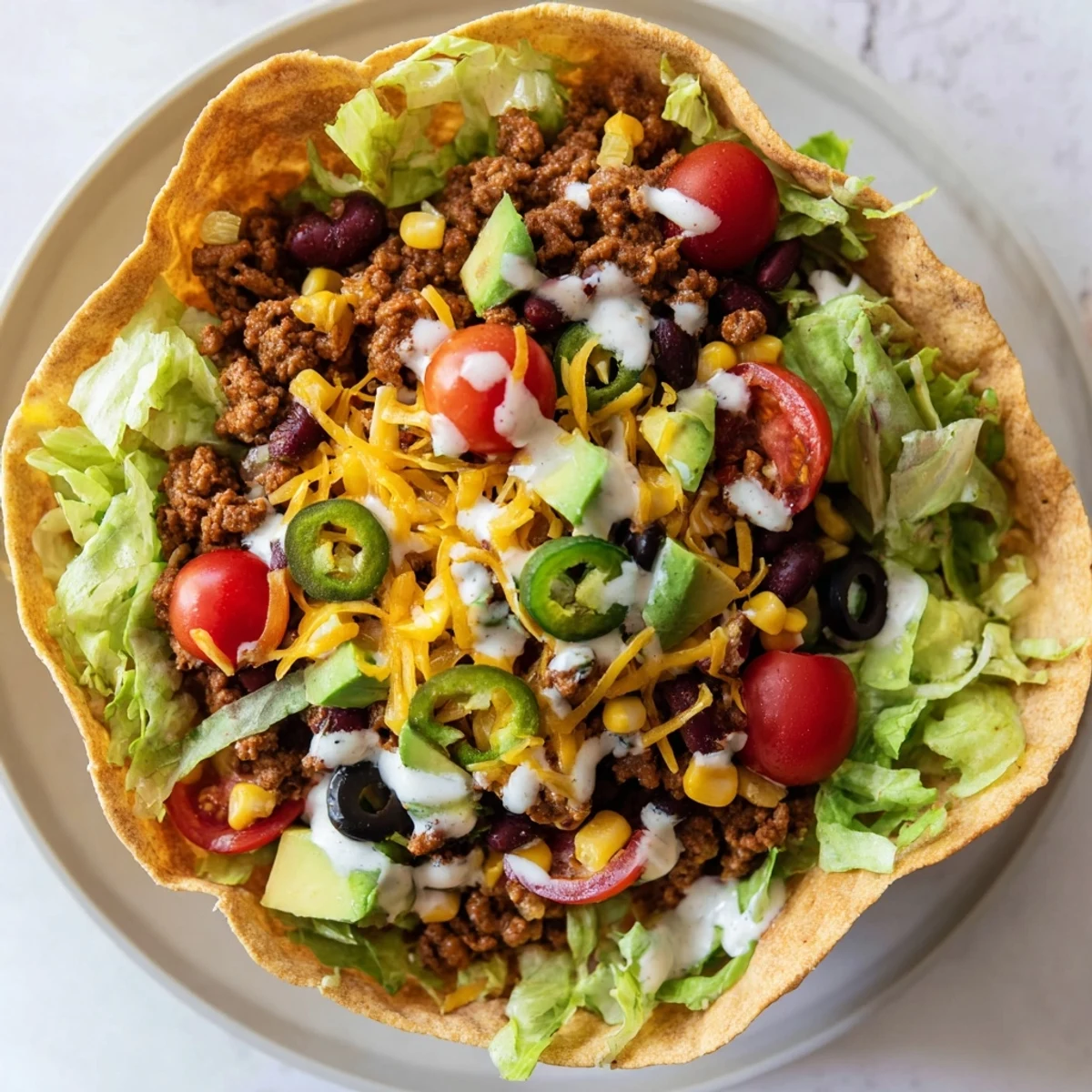 Crispy homemade tortilla bowl filled with seasoned ground beef, black beans, corn, avocado, and melted cheddar cheese.