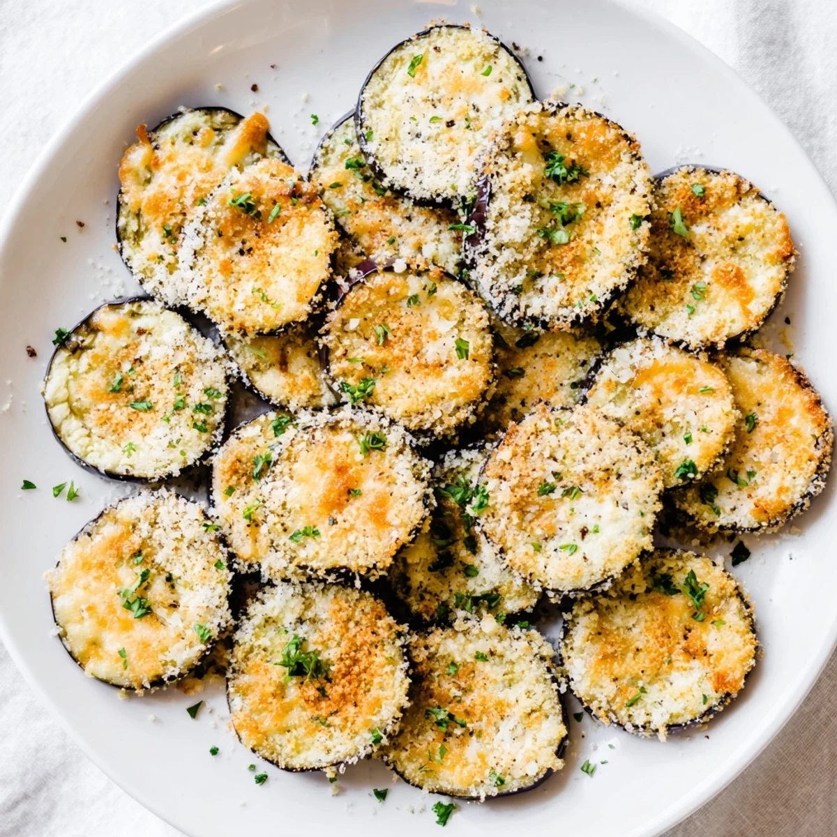 Golden Mediterranean roasted eggplant slices topped with melted Parmesan crisps, served warm from the oven as an appetizer.  