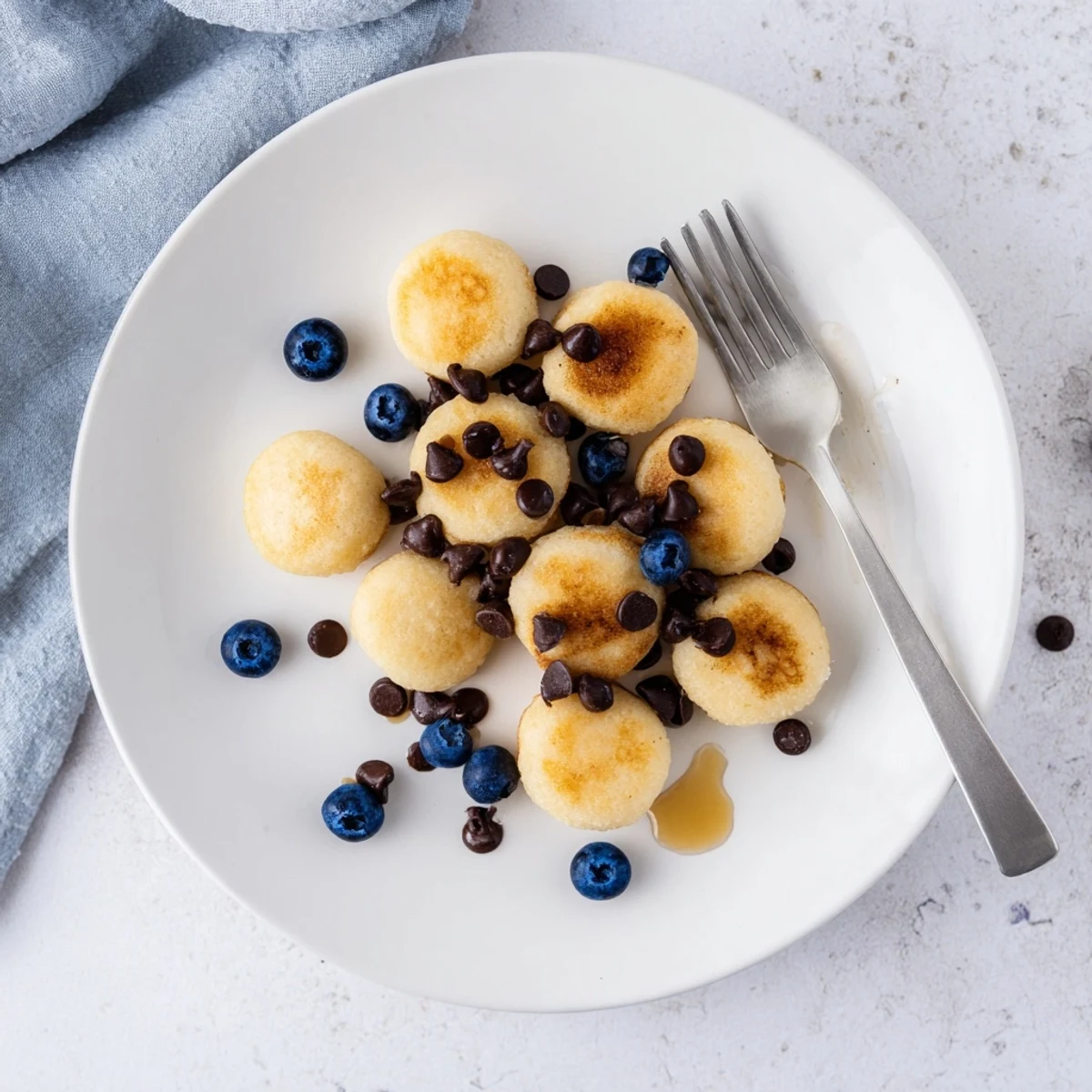 Fluffy bite-sized Pancake Poppers arranged on a plate, perfect for dipping in chocolate sauce at breakfast.