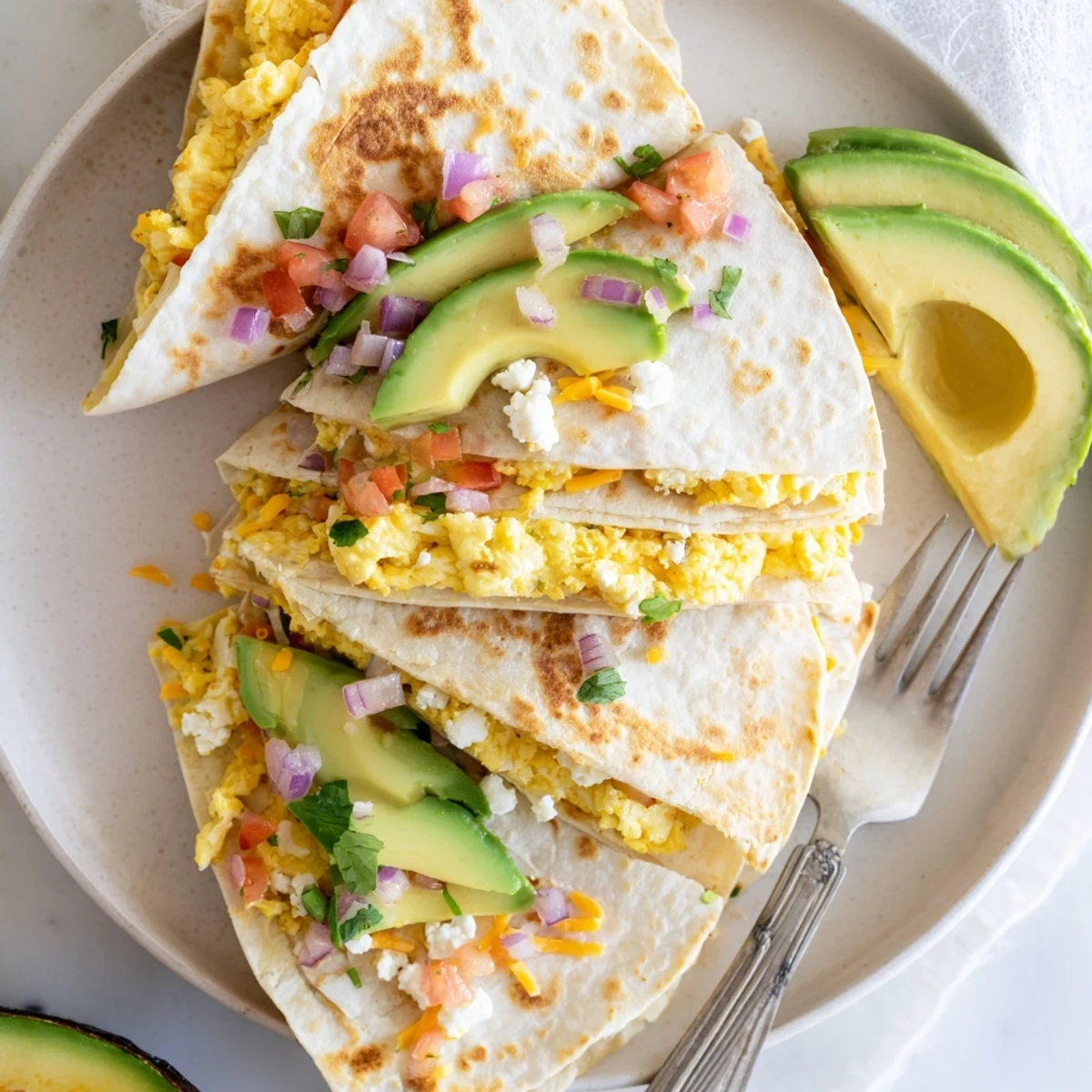 Steam rises from the warm tortilla as the creamy avocado and fluffy scrambled eggs peek through the melted cheese.  