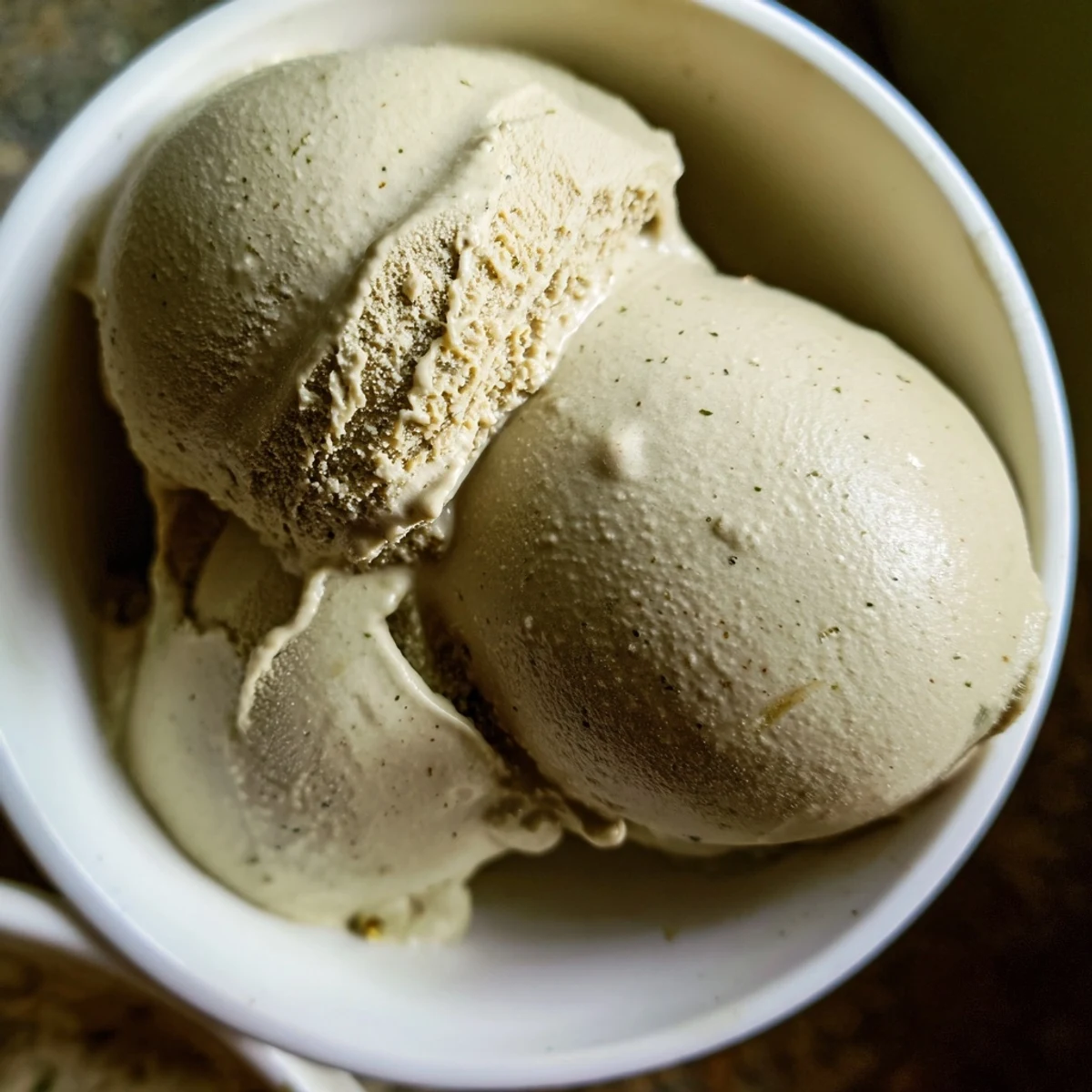 Homemade Hojicha Ice Cream served in rustic ceramic bowls with a drizzle of syrup, showcasing the smooth, roasted flavor perfect for an afternoon treat.