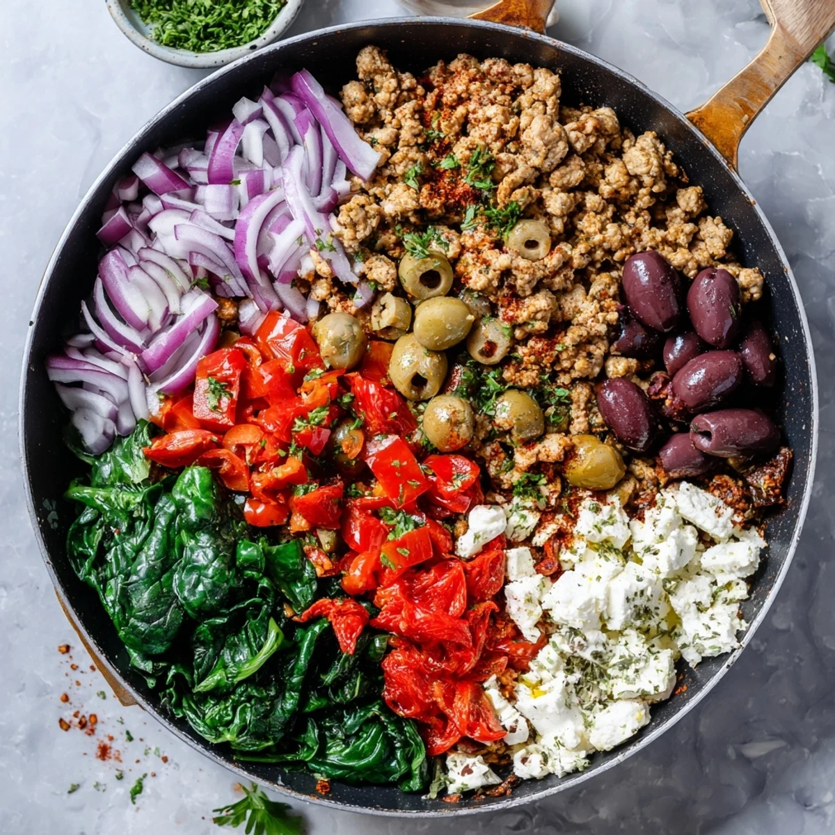 Freshly cooked Mediterranean Keto Skillet with Ground Chicken, Olives & Feta in a hot cast-iron skillet with glistening olive oil.