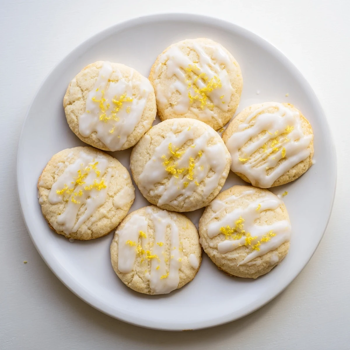 Delicate Italian-inspired Limoncello Cookies with a buttery texture and zesty aroma, displayed beside a glass of limoncello liqueur for serving.