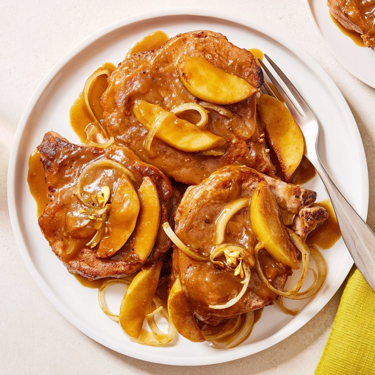 Golden seared apple butter pork chops resting in a rich cinnamon-spiced glaze with caramelized apple slices