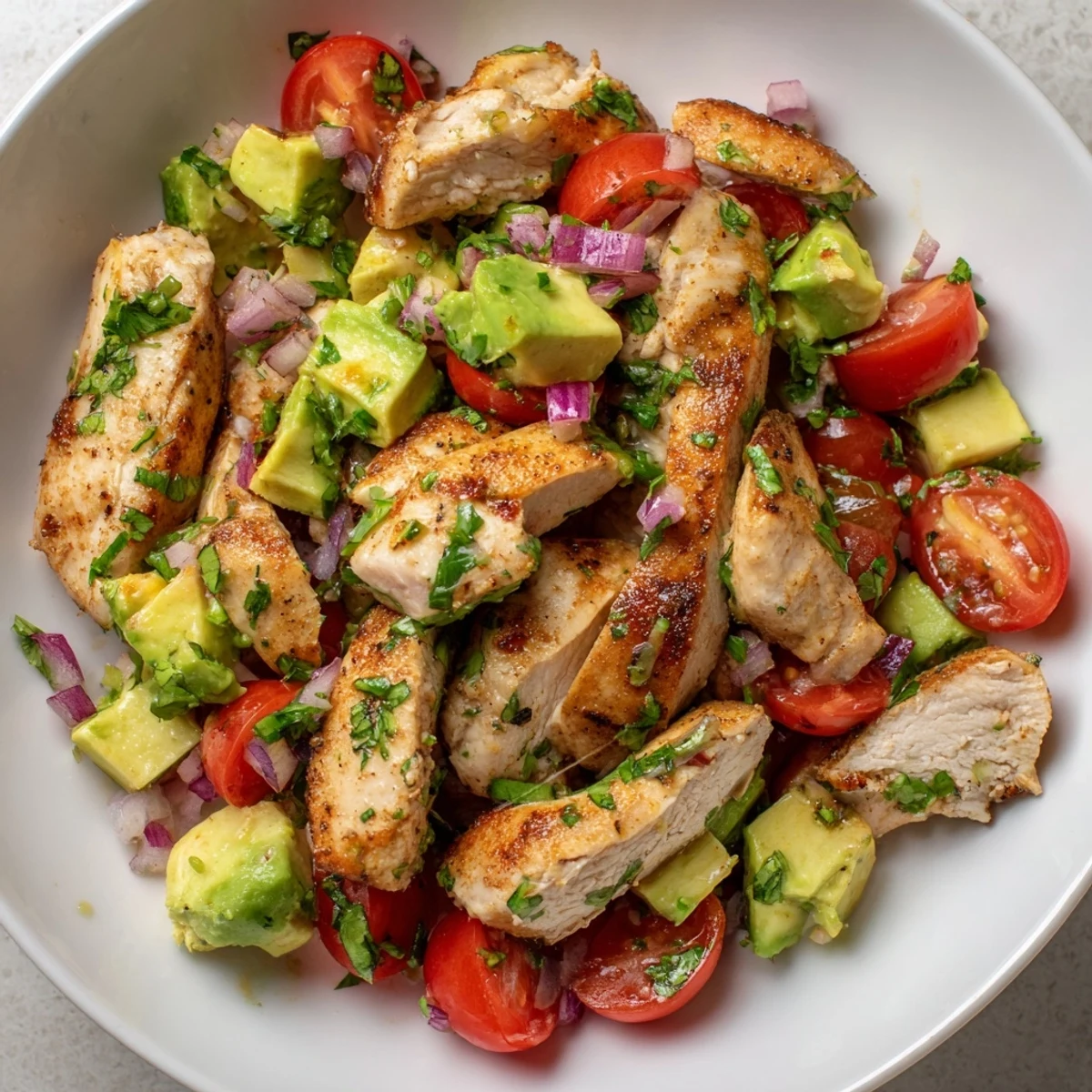 Golden pan-seared chicken slices served over fresh avocado salad with honey lime dressing