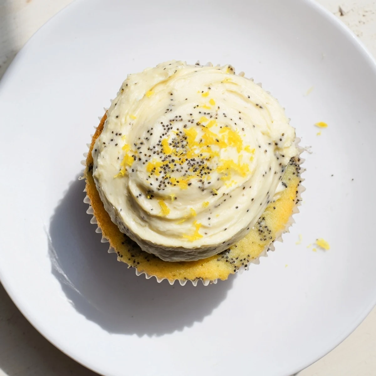 Golden lemon poppy seed cupcakes topped with fluffy cream cheese frosting and sprinkled with fresh lemon zest