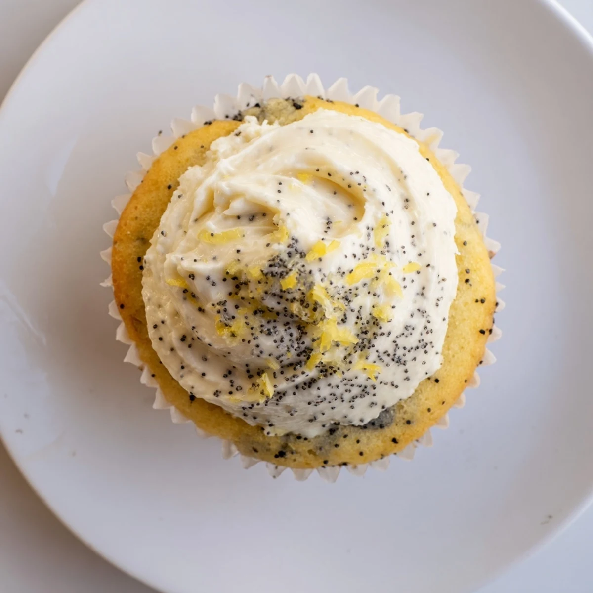 Swirled lemon cream cheese frosting atop moist lemon poppy seed cupcakes on a rustic wooden board