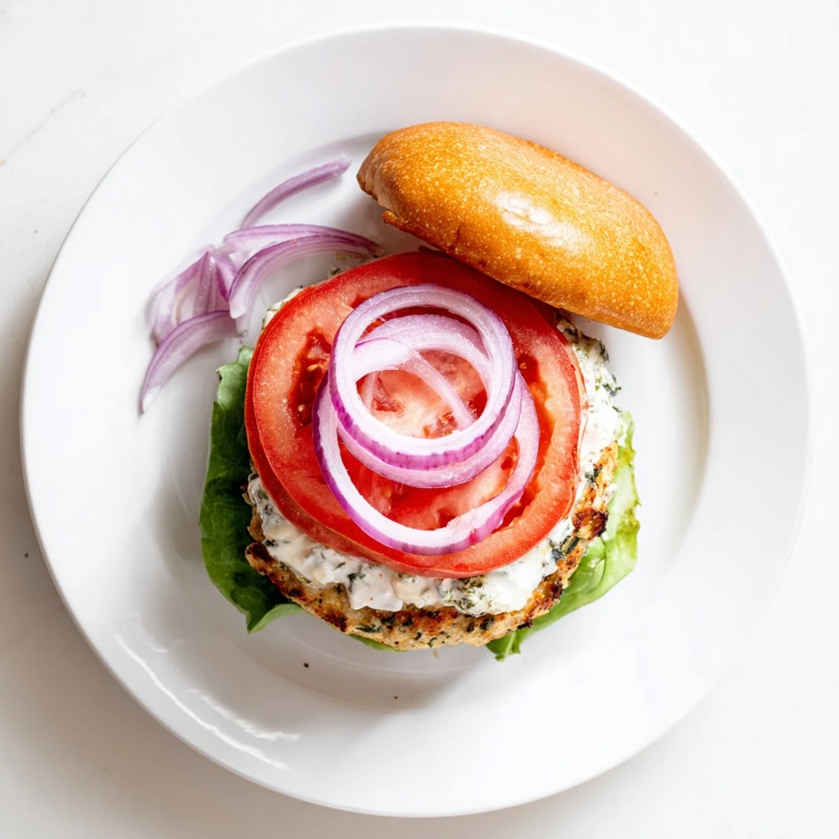 Succulent grilled chicken patties with feta and herbs served on burger buns with creamy homemade tzatziki