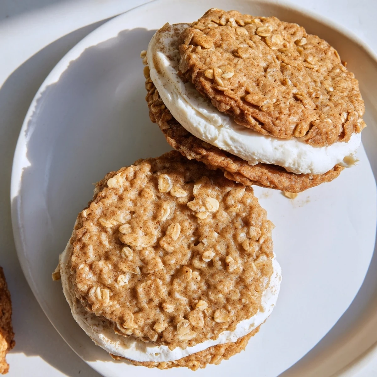 Close-up of chewy oatmeal cream pie with thick vanilla buttercream spread between textured cookies