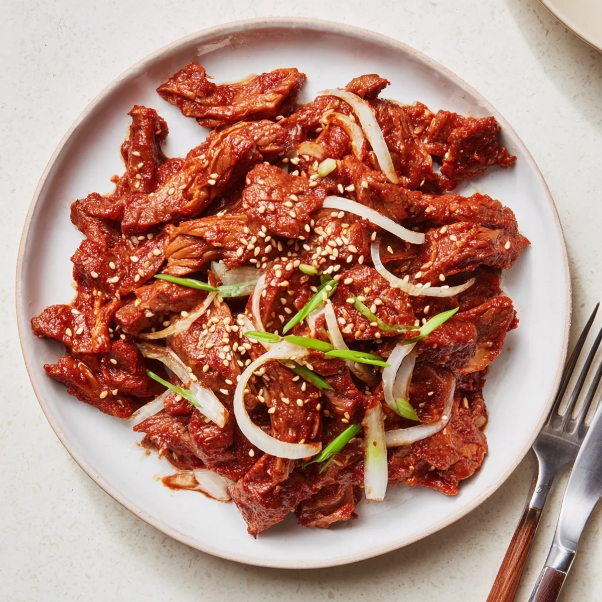 Shredded Slow Cooker Korean Beef served over white rice with fresh green onion garnish
