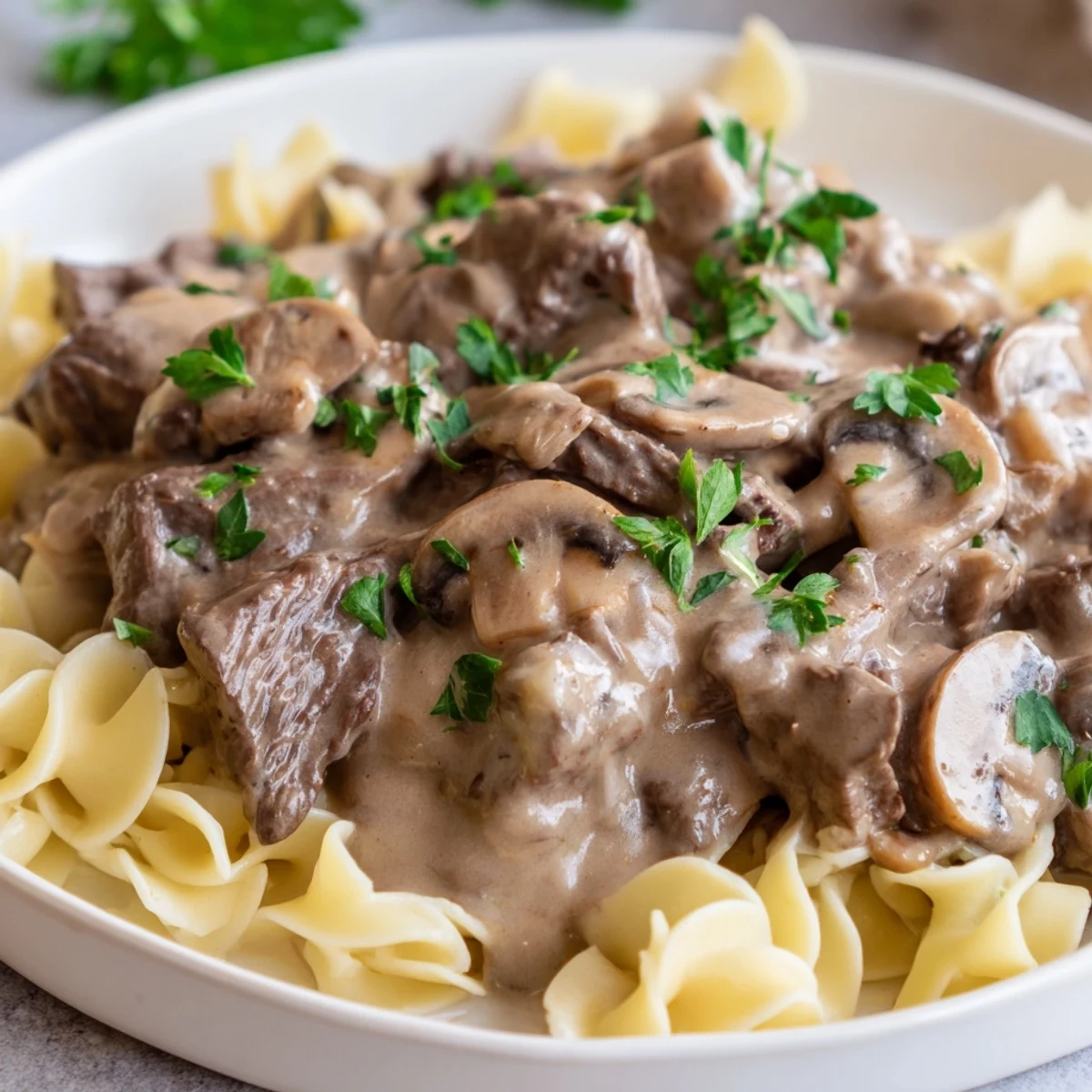 Classic beef stroganoff featuring rich mushroom sauce with fresh parsley garnish on white plate