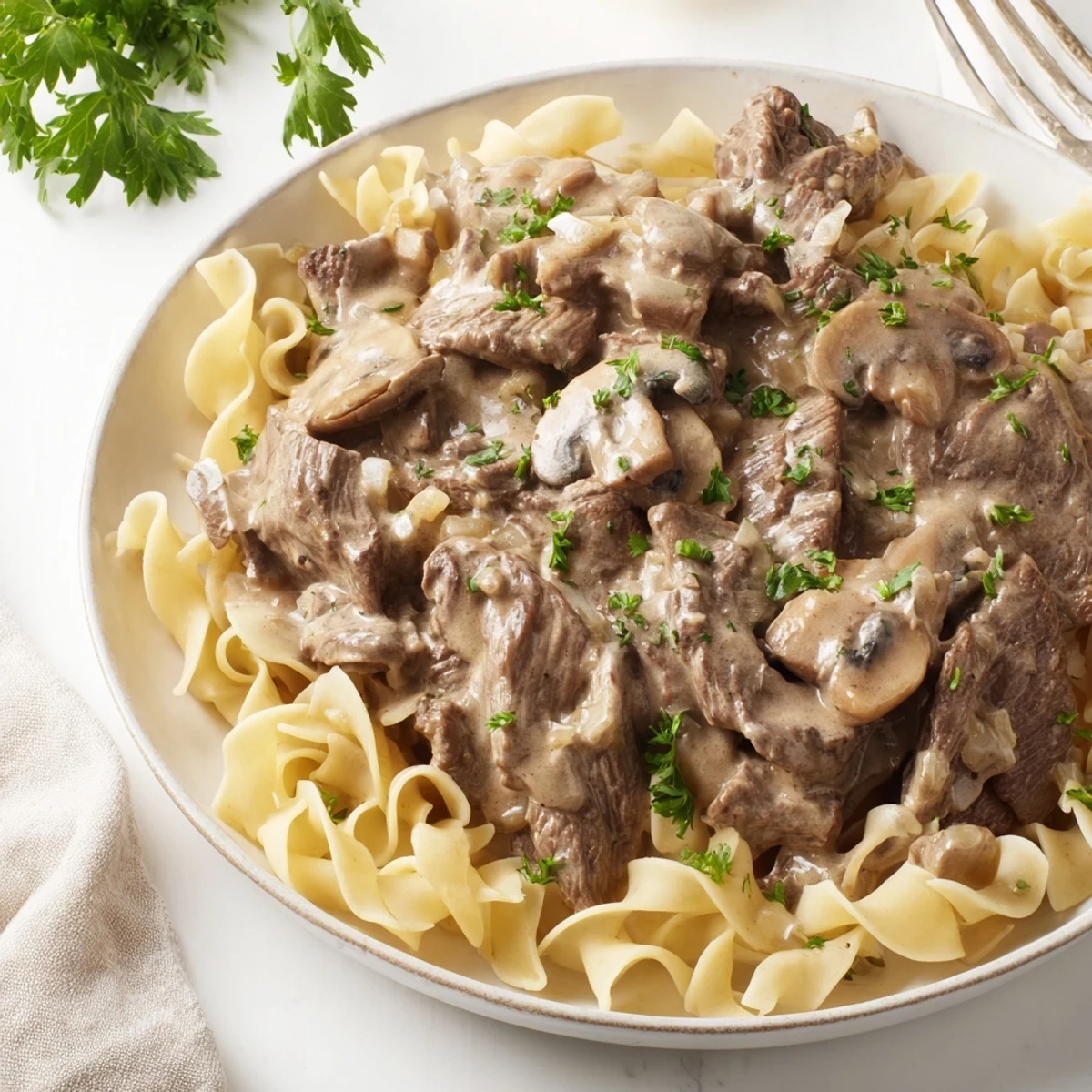 Creamy beef stroganoff with tender beef slices and mushrooms served over egg noodles