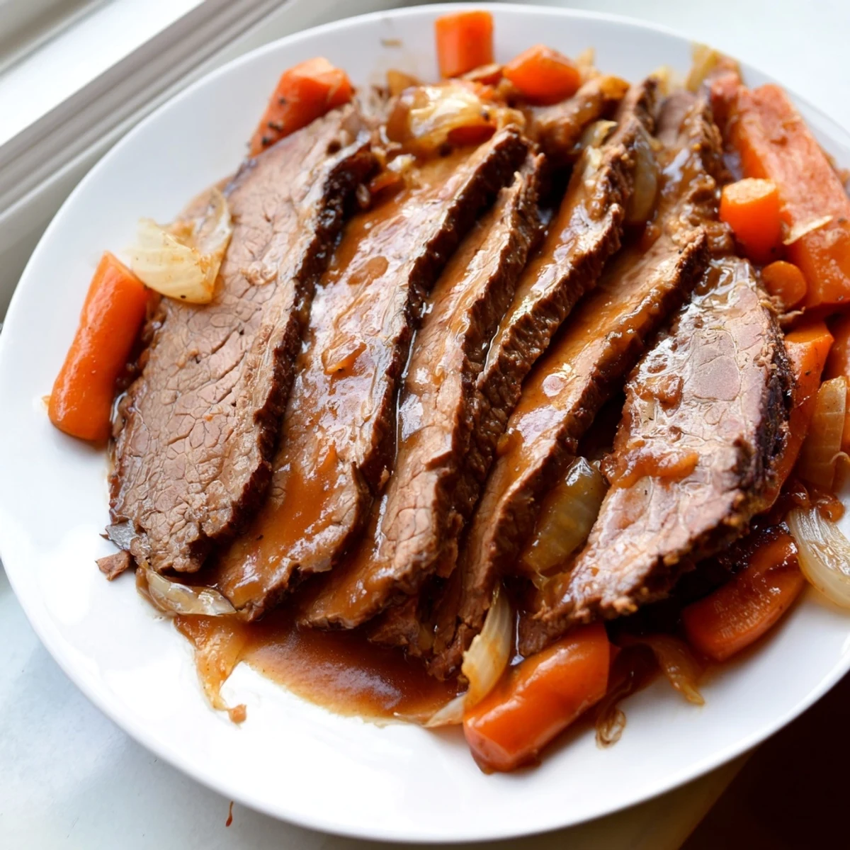 Tender slow cooker beef brisket slices plated with roasted vegetables and rich glossy sauce