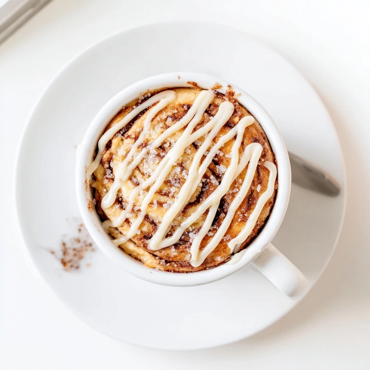 Fluffy microwave cinnamon roll mug cake drizzled with vanilla cream cheese icing for a healthy breakfast