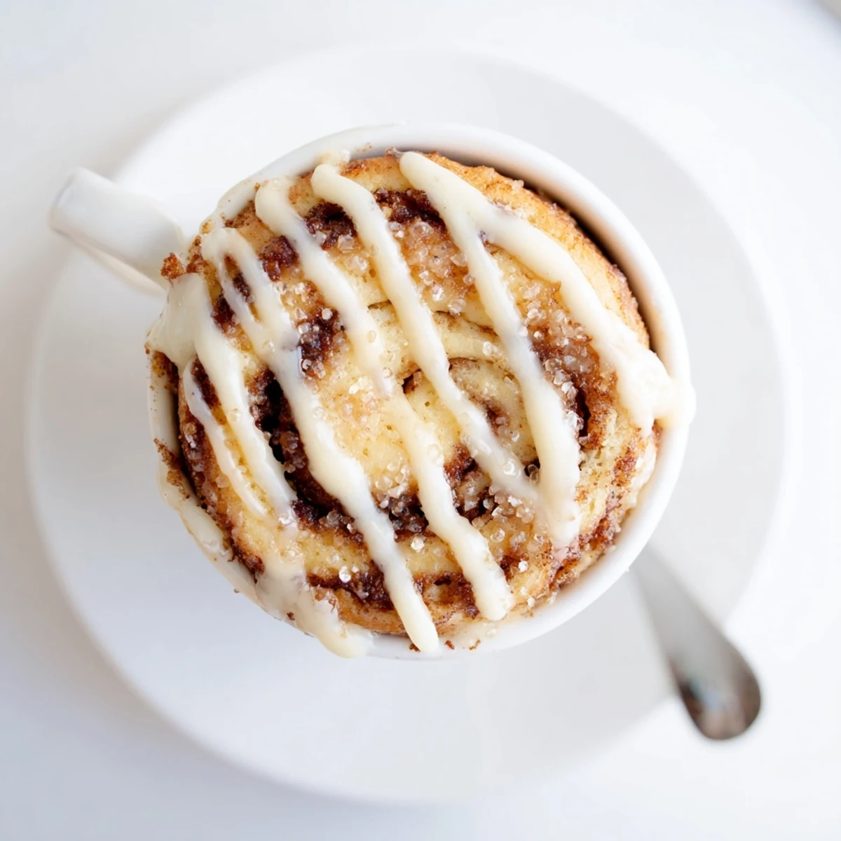 High protein cinnamon roll mug cake with melted cinnamon sugar swirl in a white ceramic mug