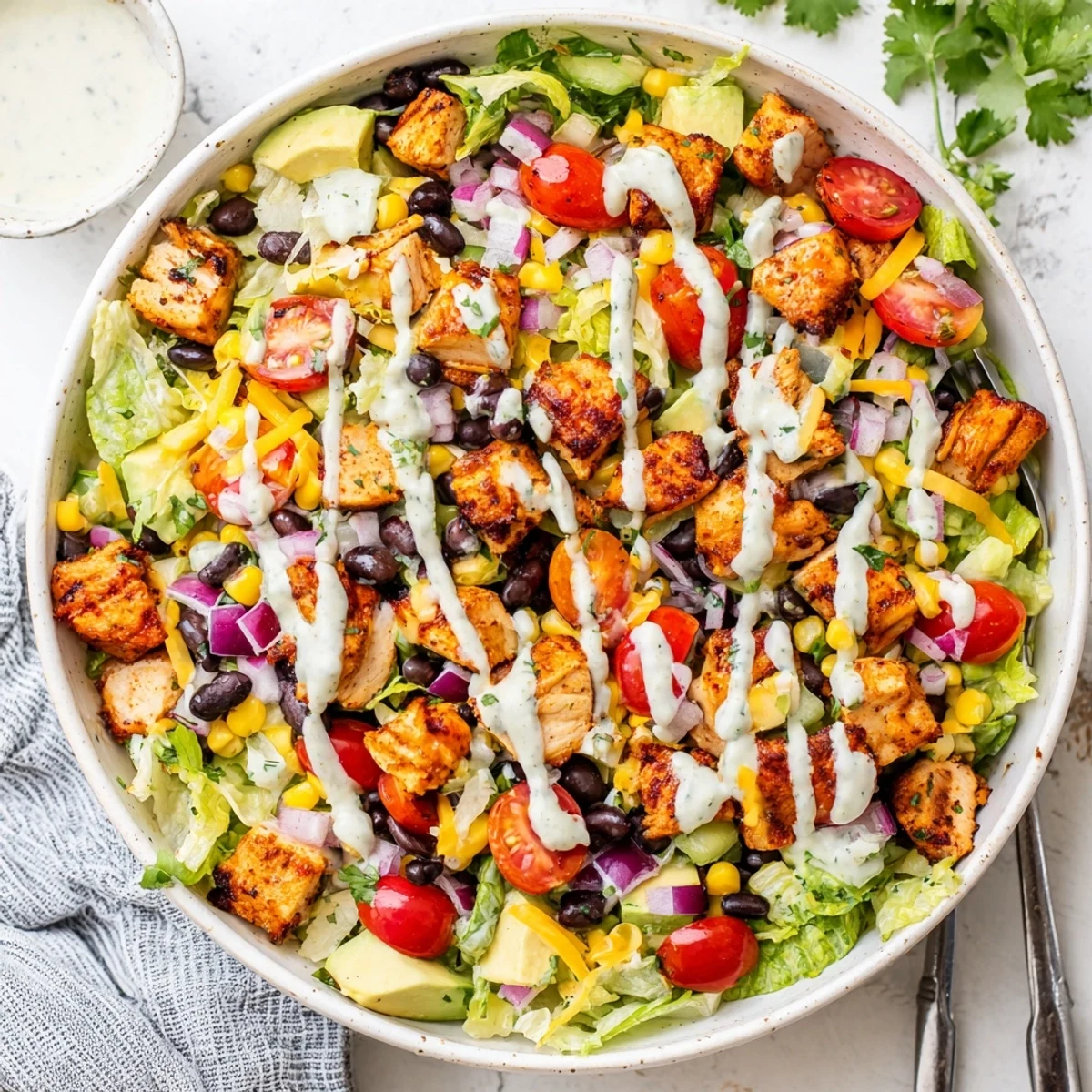 Vibrant chopped salad bowl showcasing healthy BBQ chicken with corn, tomatoes, and drizzled yogurt dressing
