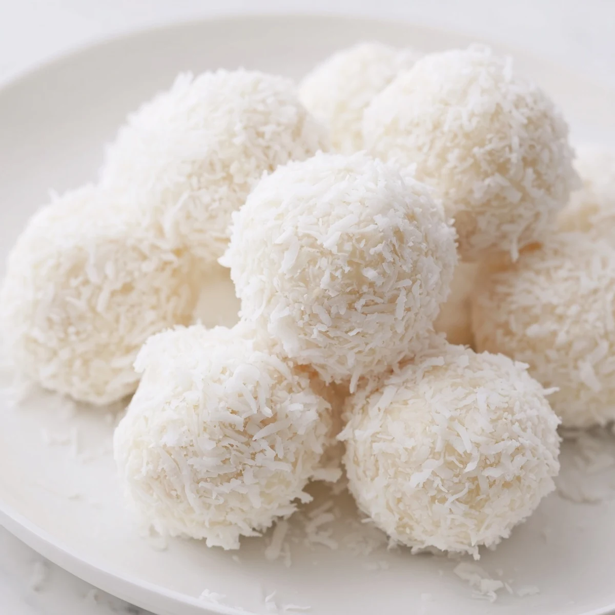 Homemade Easter bunny coconut tails displayed on decorative platter with white snowy powdered sugar coating