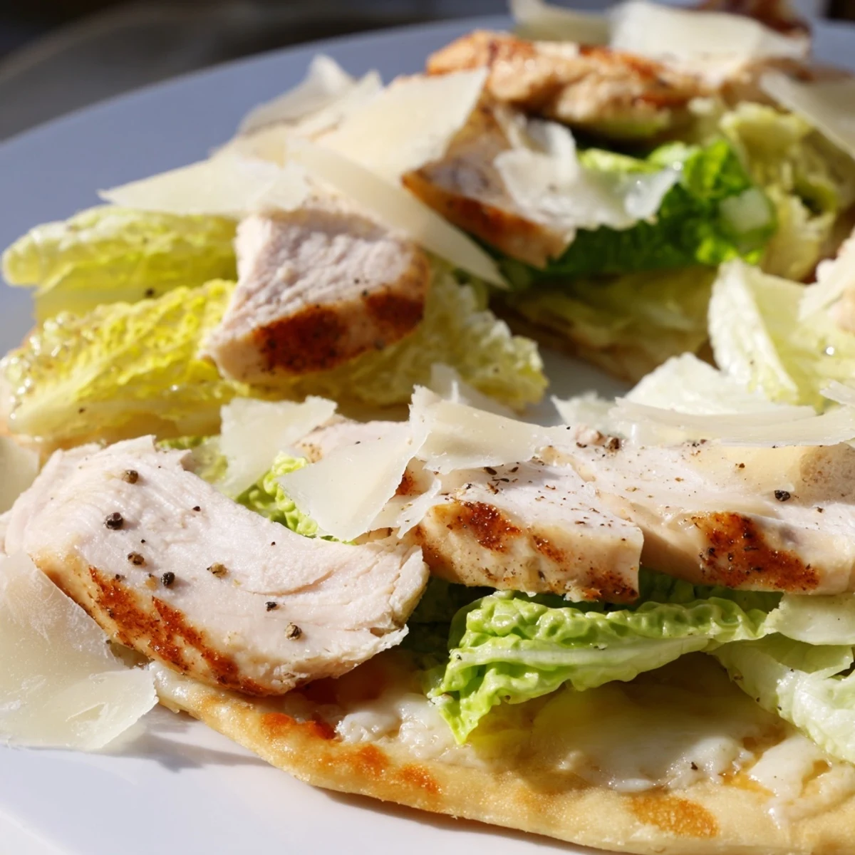 Savory chicken Caesar flatbread with grilled chicken strips, creamy dressing, and fresh lettuce garnish
