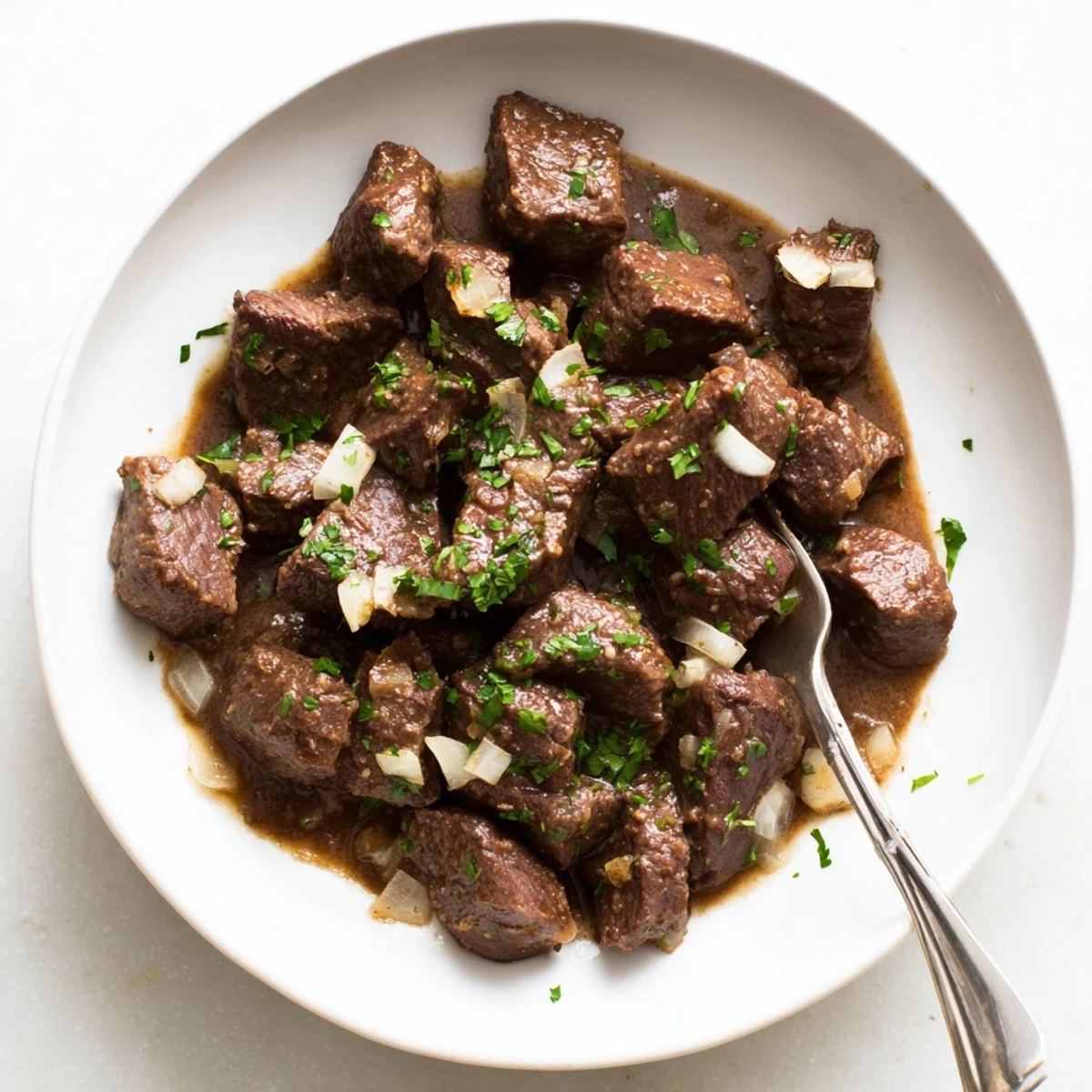 Golden brown Crockpot steak bites glistening with butter and fresh parsley garnish