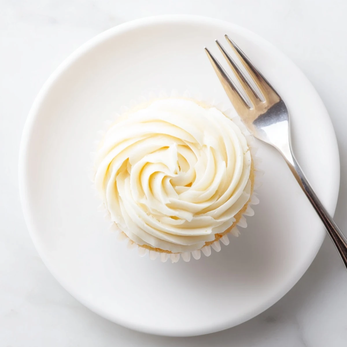 Golden vanilla cupcakes topped with fluffy white buttercream frosting and colorful sprinkles