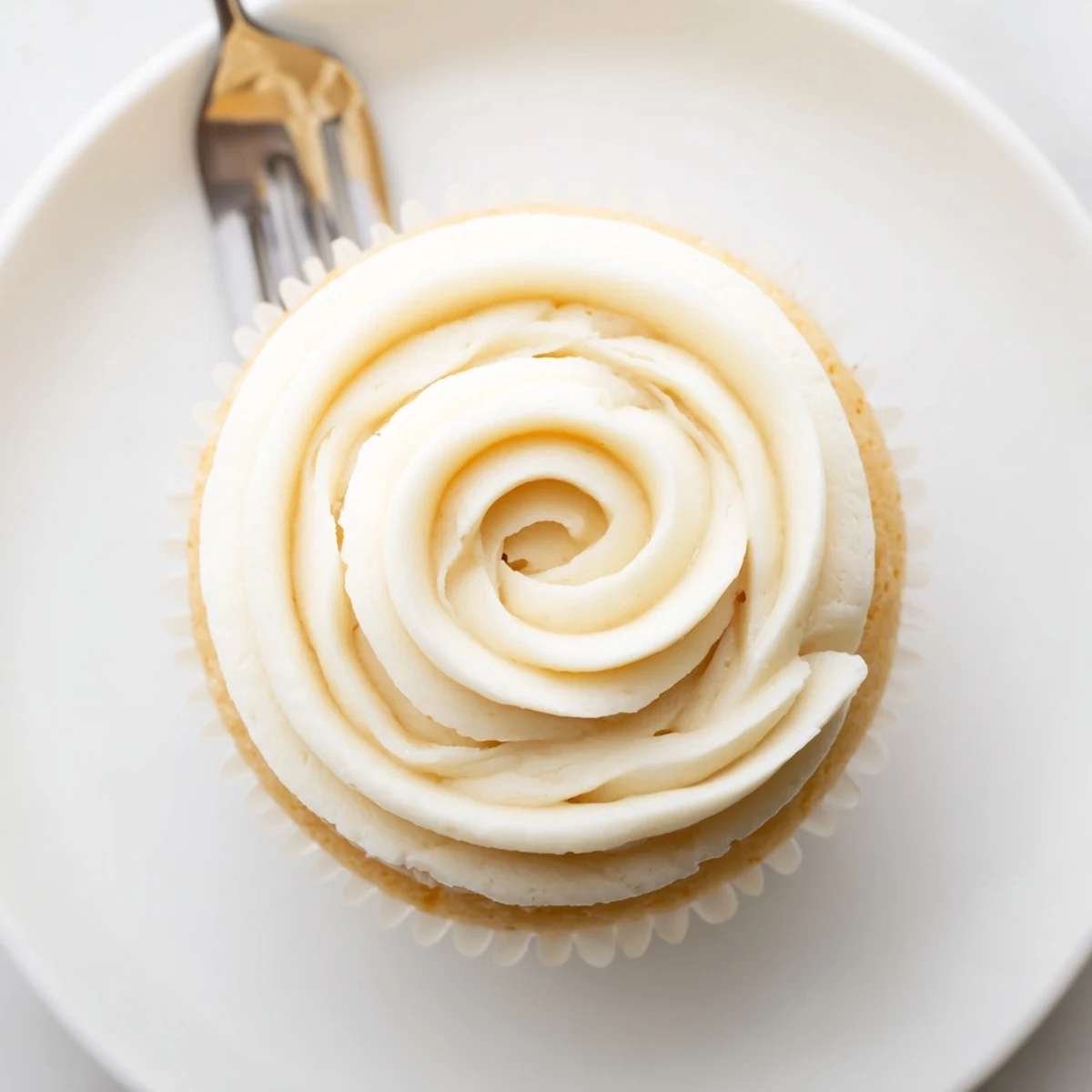 Light and fluffy vanilla cupcakes with piped vanilla buttercream on a white serving plate