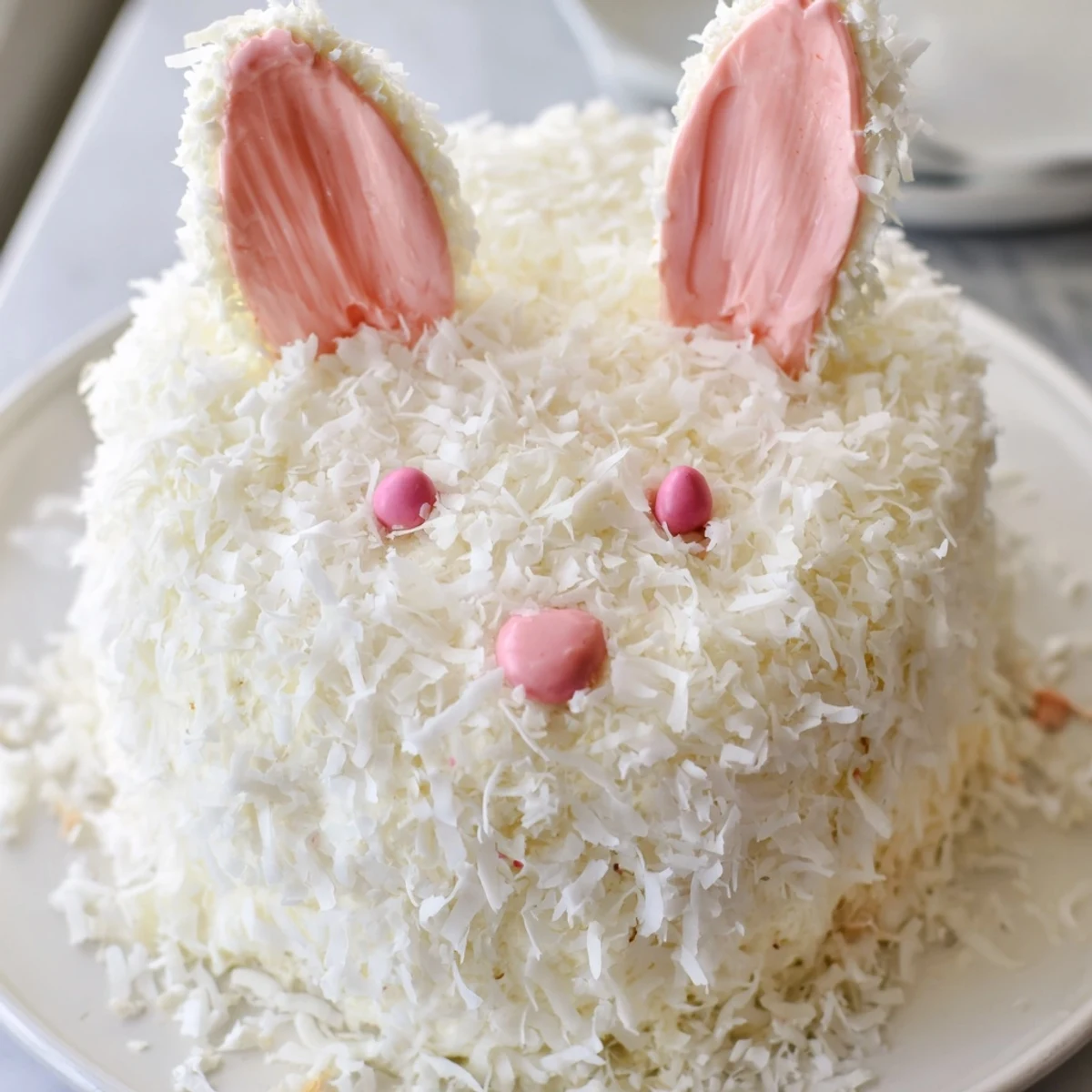 Adorable Easter bunny cake with fluffy coconut fur and pink buttercream bow tie