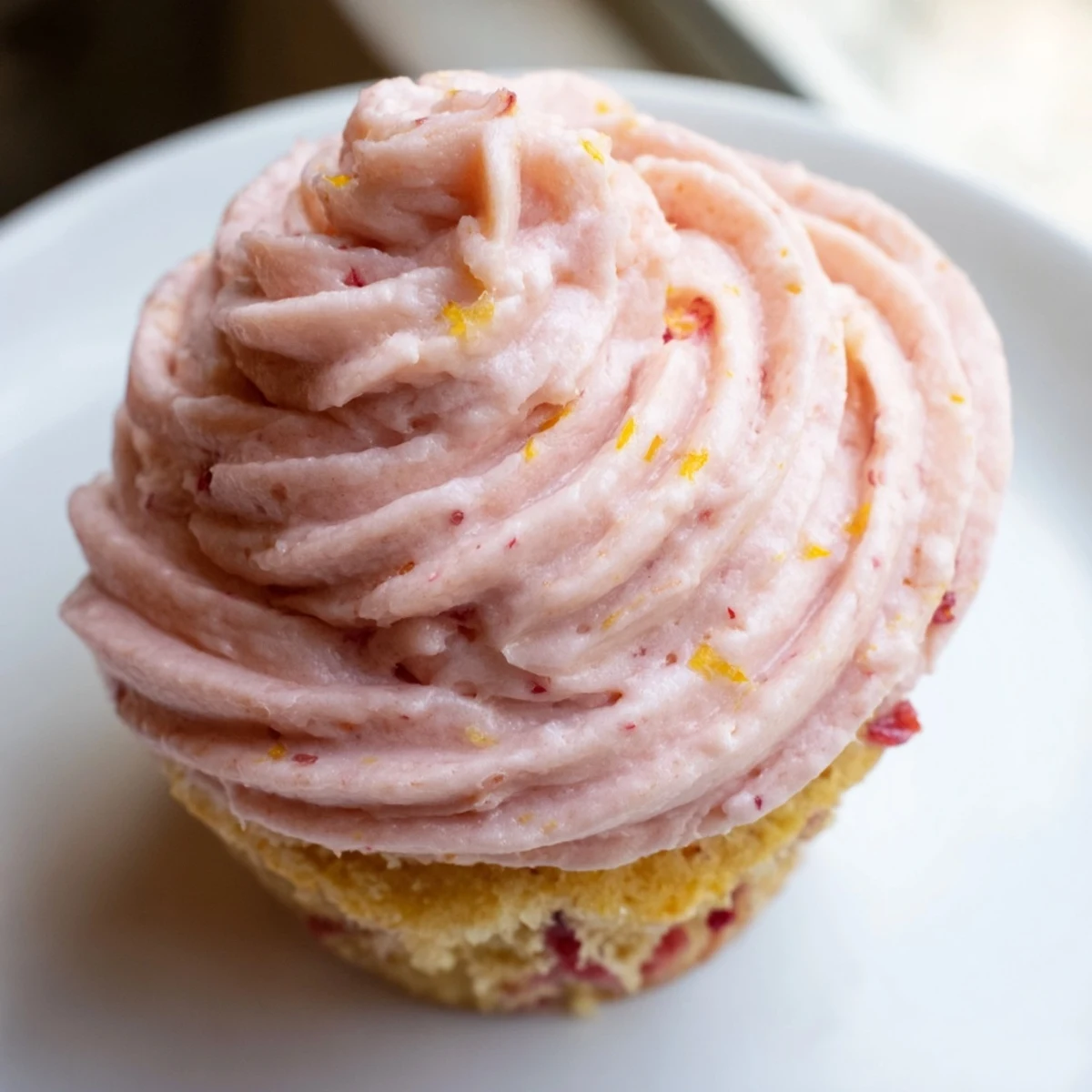 Pink strawberry lemonade cupcakes with swirled buttercream frosting topped with fresh berry slices