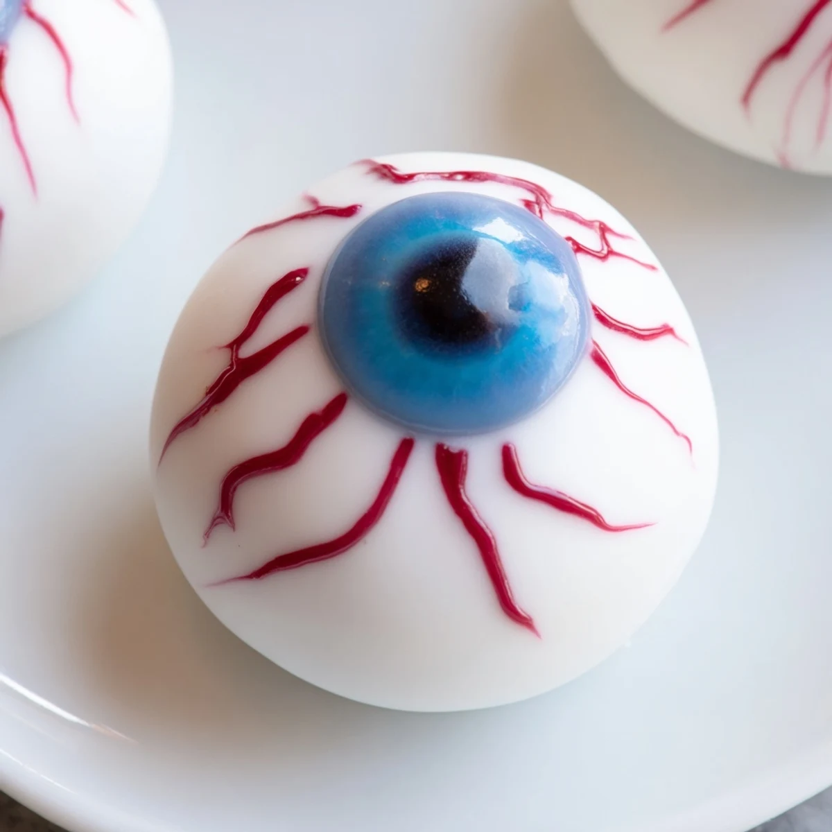 Glossy white chocolate Halloween Cake Eyeballs with colorful irises on parchment