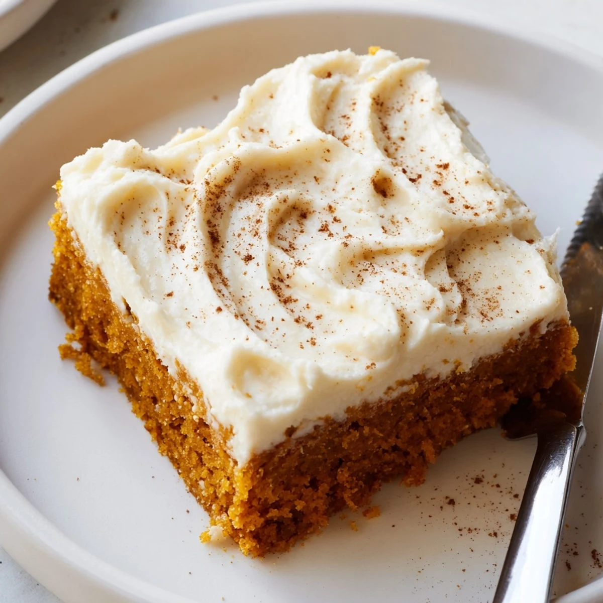 Moist spiced pumpkin bars swirled with thick cream cheese frosting ready for a crowd