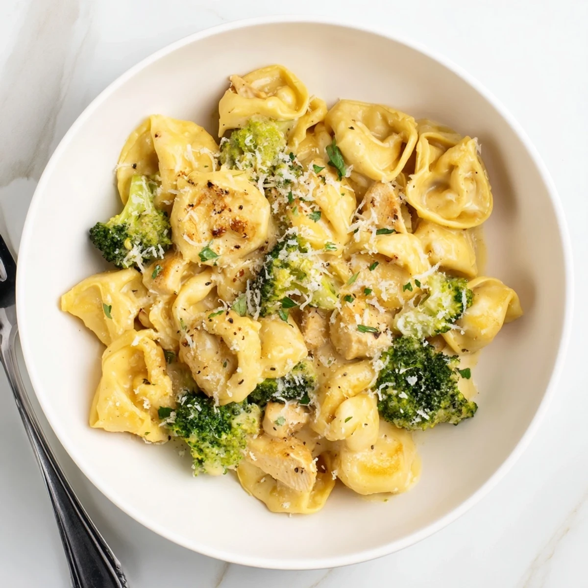 Plate of Creamy Garlic Parmesan Tortellini Chicken Broccoli Recipe, garnished with parsley  