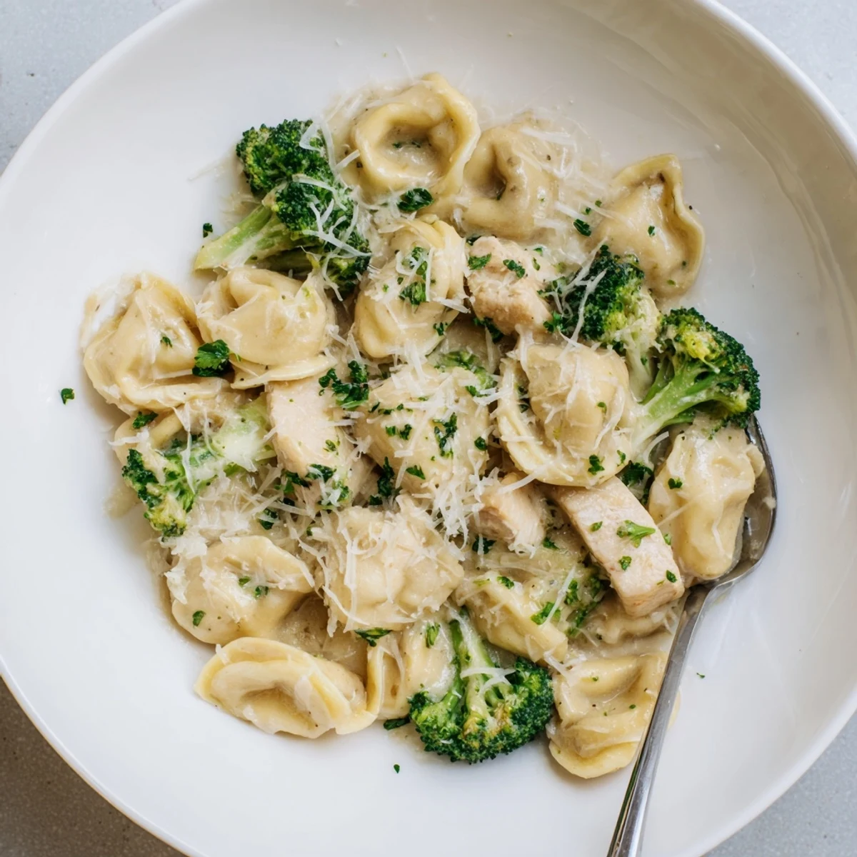 Forkful of cheesy goodness from Creamy Garlic Parmesan Tortellini Chicken Broccoli Recipe, steaming